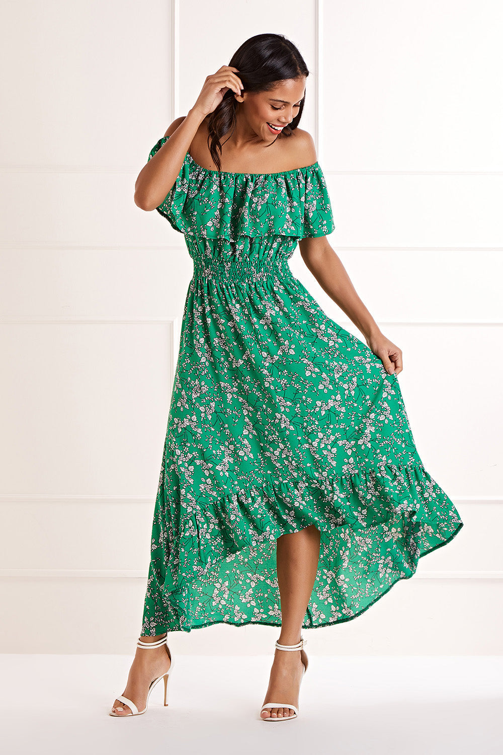 Yumi Green Bardot Asymmetric Maxi Dress showing the off-the-shoulder ruffled neckline ditsy floral print waist-tapering silhouette and full-length asymmetric hemline in green