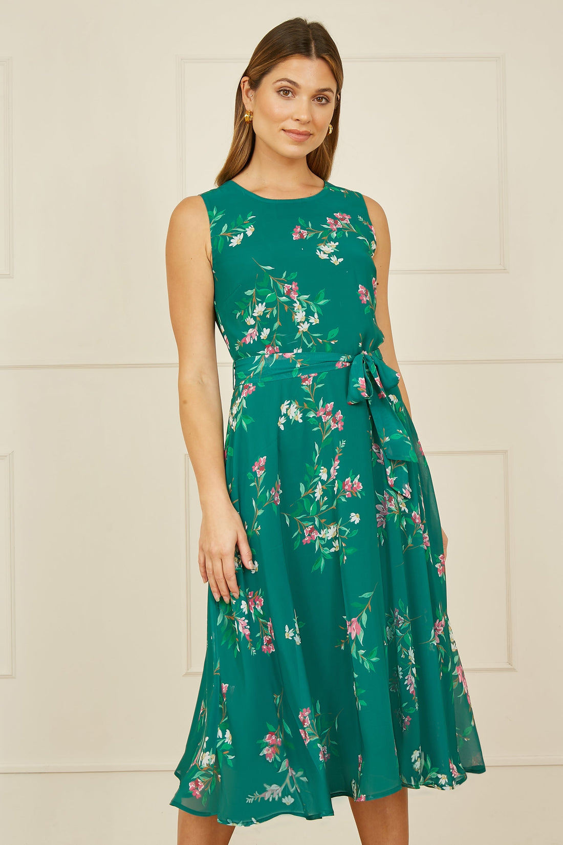 Yumi Green Daisy Print Skater Dress full length front view showing the fit and flare silhouette with all-over daisy print and self-tie waist in midi length