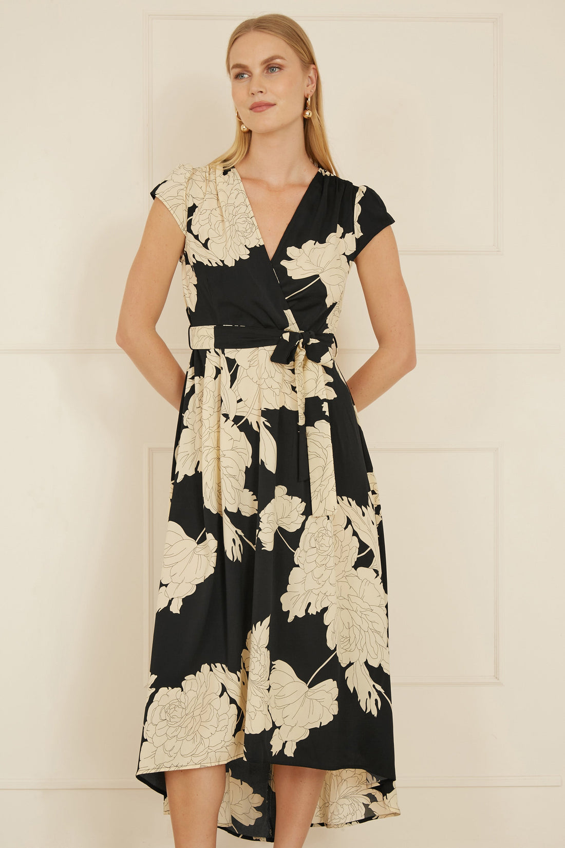 Yumi Black Blossom Print Wrap Midi With Dipped Hem — front view showing the wrap-style bodice, short flutter sleeves, self-tie waist and dipped hem with frill trim, featuring a delicate blossom print on a black base