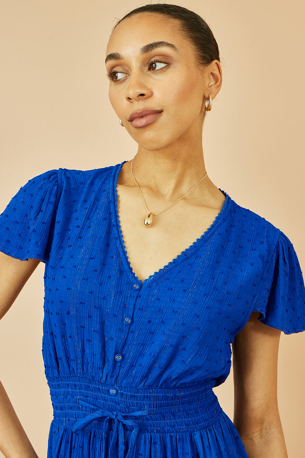Yumi Blue Button Detail Midi Dress with Ruched Waist and Metallic Thread full length front view showing the V neckline fluttery sleeves ruched waist button details and metallic shimmer in the blue viscose fabric
