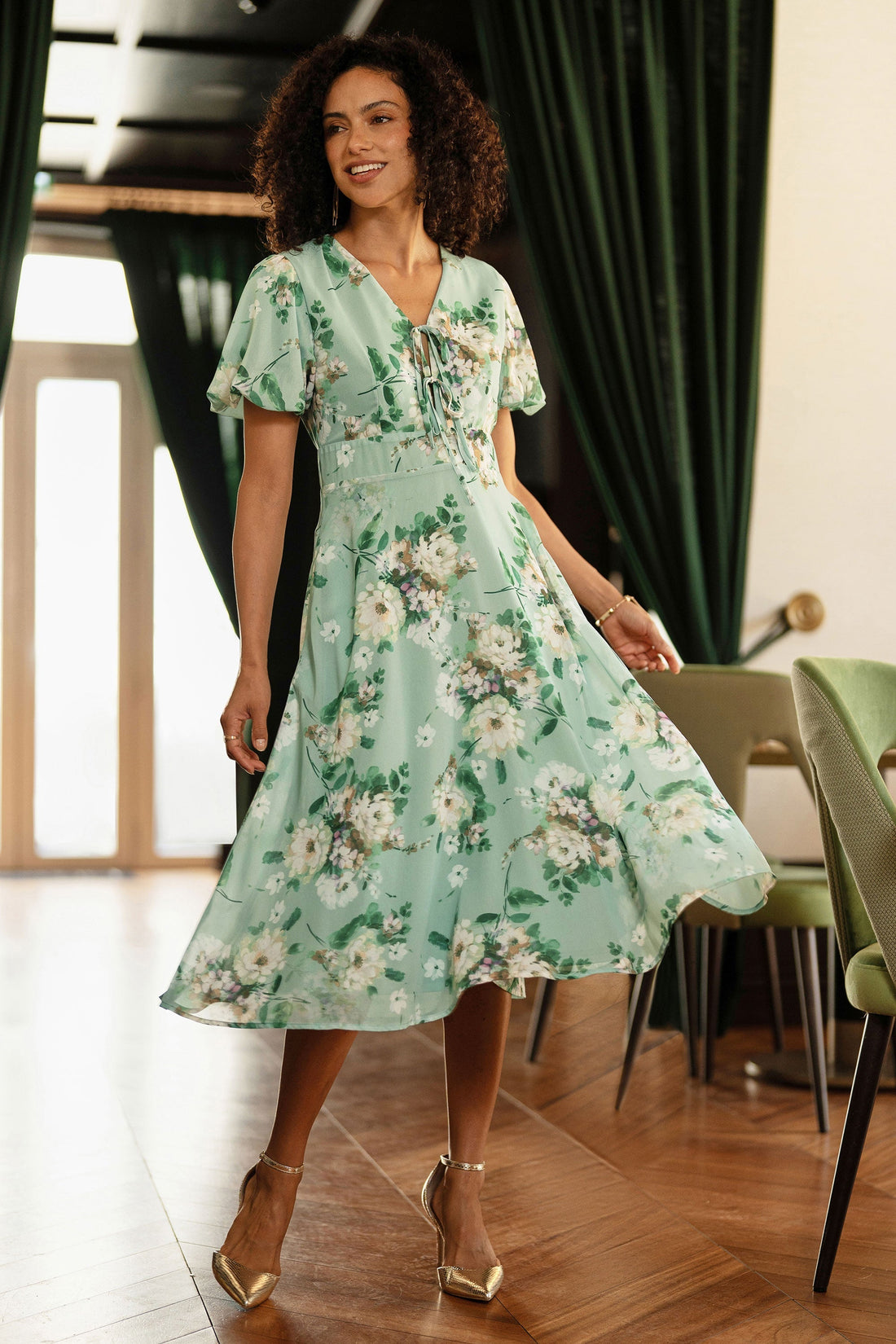 Yumi Mint Floral Tea Dress with Front Ties showing the soft mint-green floral print flutter sleeves V-neckline lace-up bust detail and flowing midi skirt at 117cm length