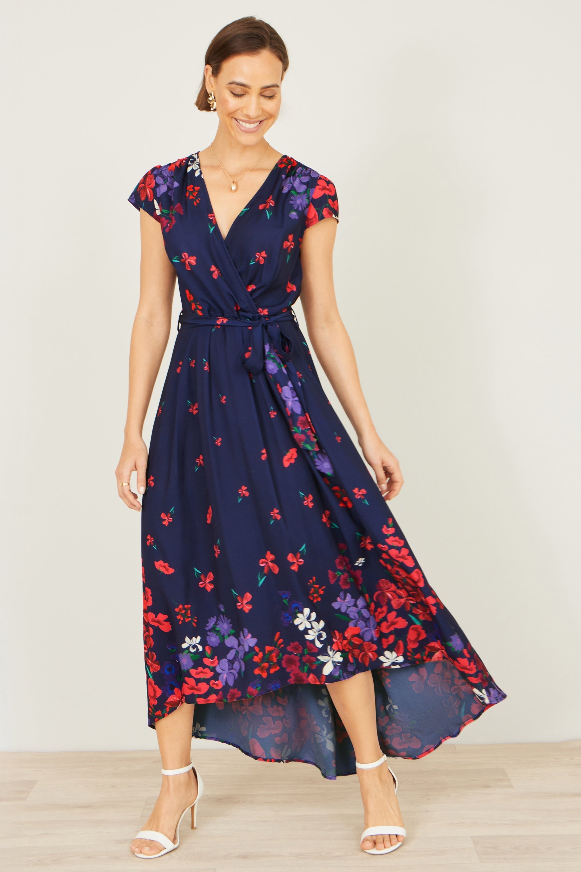 Yumi navy floral mirror wrap dress with dip hem shown on a model in a lifestyle setting, featuring a bold floral print and elegant wrap silhouette
