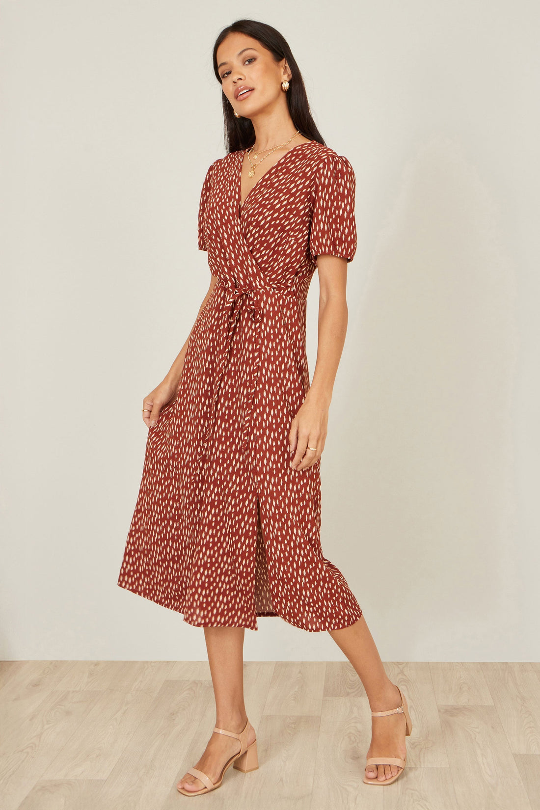 Yumi Brown Spot Wrap Midi Dress in warm brown with spot print showing the flattering wrap silhouette V neckline midi length and split hemline on a model
