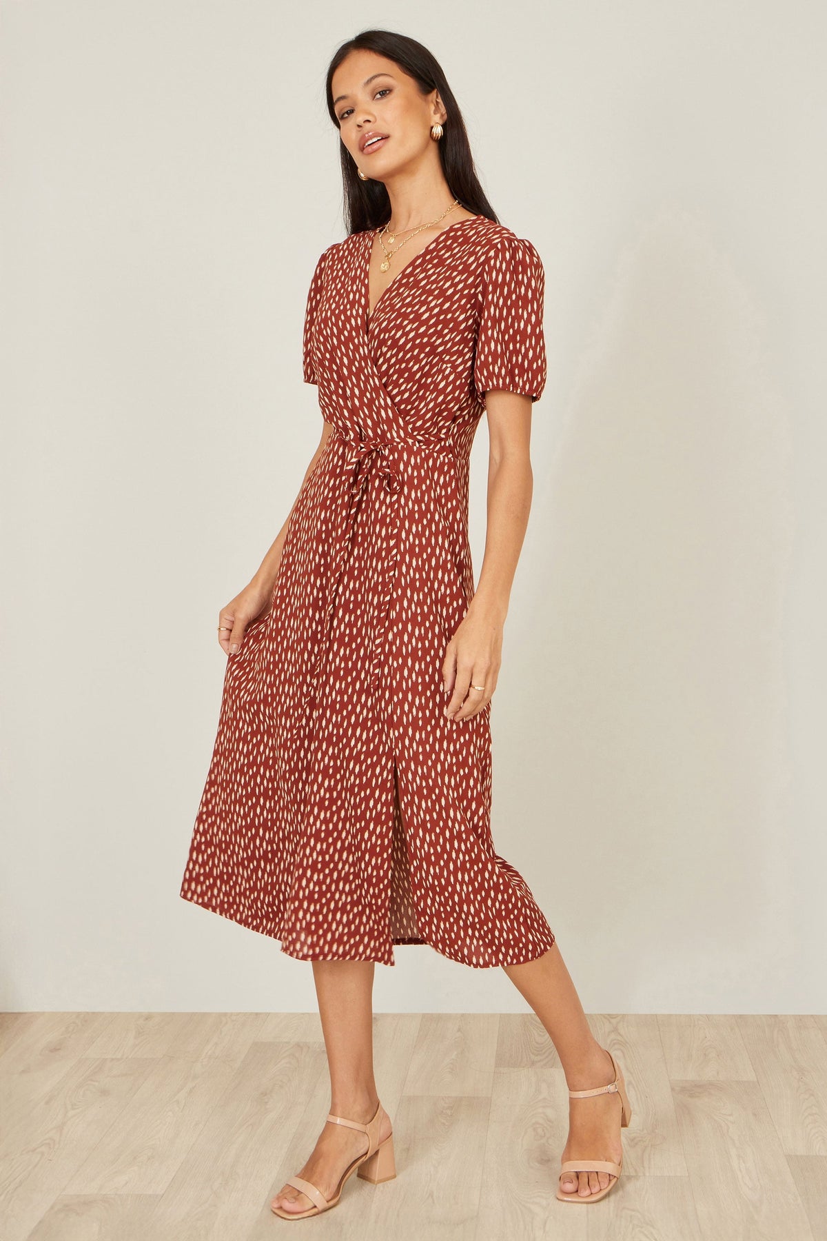 Yumi Brown Spot Wrap Midi Dress in warm brown with spot print showing the flattering wrap silhouette V neckline midi length and split hemline on a model