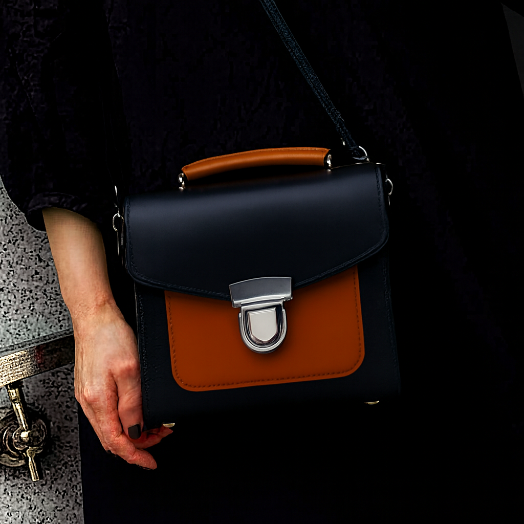 Woman carrying the Zatchels Handmade Leather Two Tone Sugarcube Handbag in Black and Burnt Orange by the top grab handle, showing the boxy structured silhouette and striking two-tone leather contrast