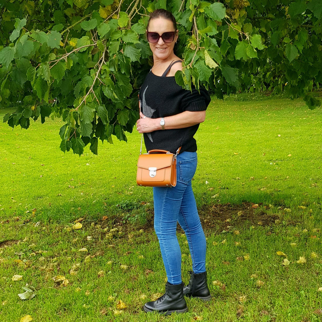 Woman carrying the Zatchels Handmade Leather Sugarcube Handbag in Burnt Orange by the top grab handle showing the structured boxy silhouette and rich warm autumnal leather tone