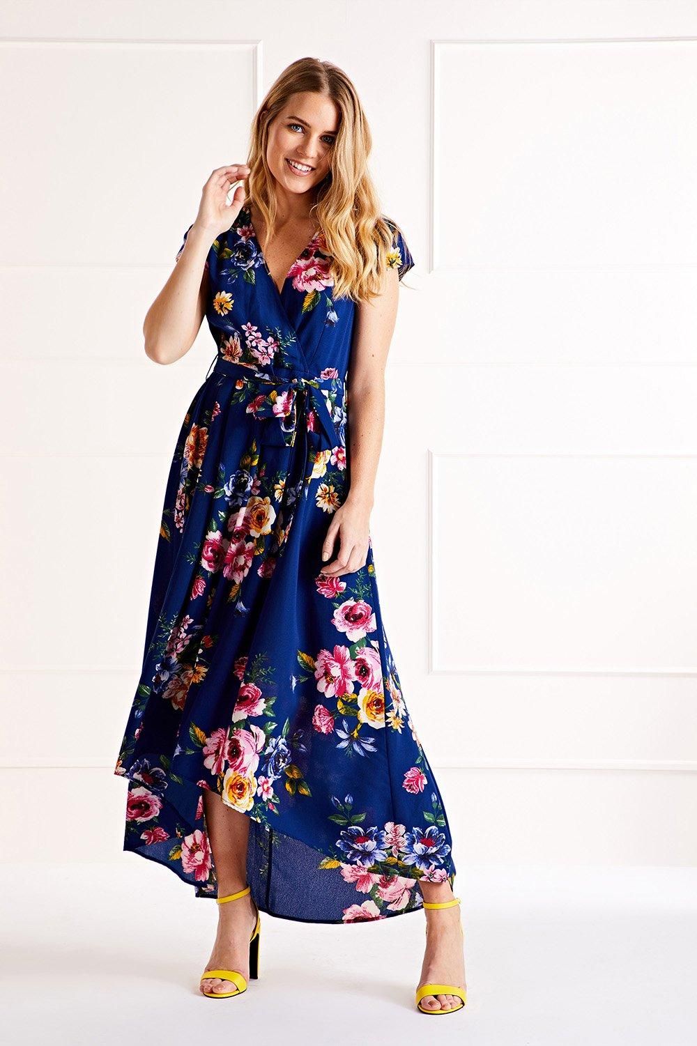 Mela Blue Floral Wrap Over Dipped Hem Midi Dress — short sleeve wrap bodice with self-tie waist and flowing dipped hem skirt in blue floral print, full length front view