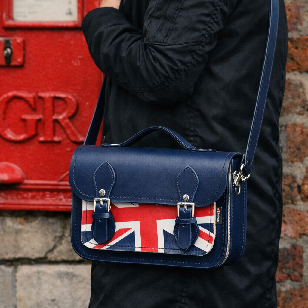 Woman wearing the Zatchels Union Jack Midi Satchel in Navy as a crossbody bag showing the iconic Union Jack leather design, navy blue background and silver nickel buckle fastenings