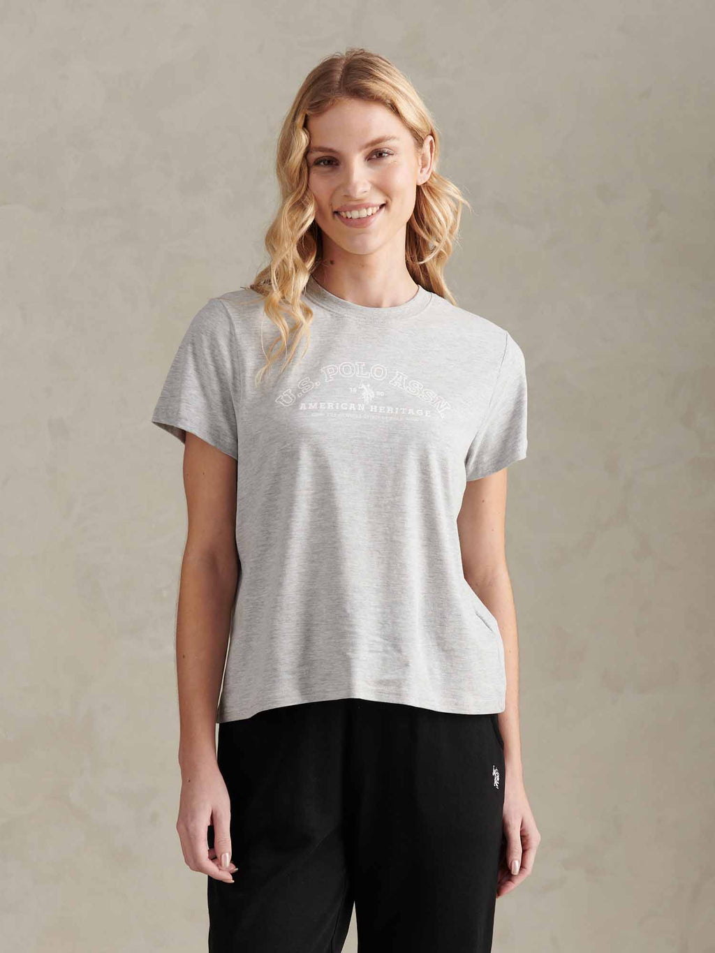 Woman wearing a gray t-shirt with a logo on a beige background